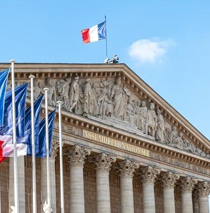 La facciata dell&#39;Assemblea Nazionale francese, adornata da bandiere e intricate sculture.