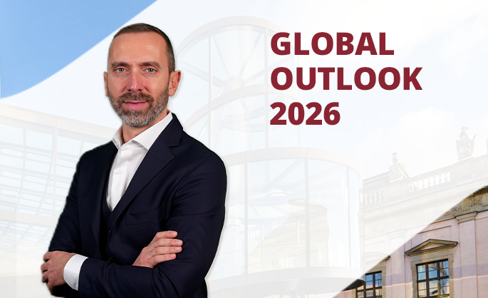 A confident man in a dark suit stands with arms crossed, smiling. The background features modern architecture and text reading "Global Outlook 2026."