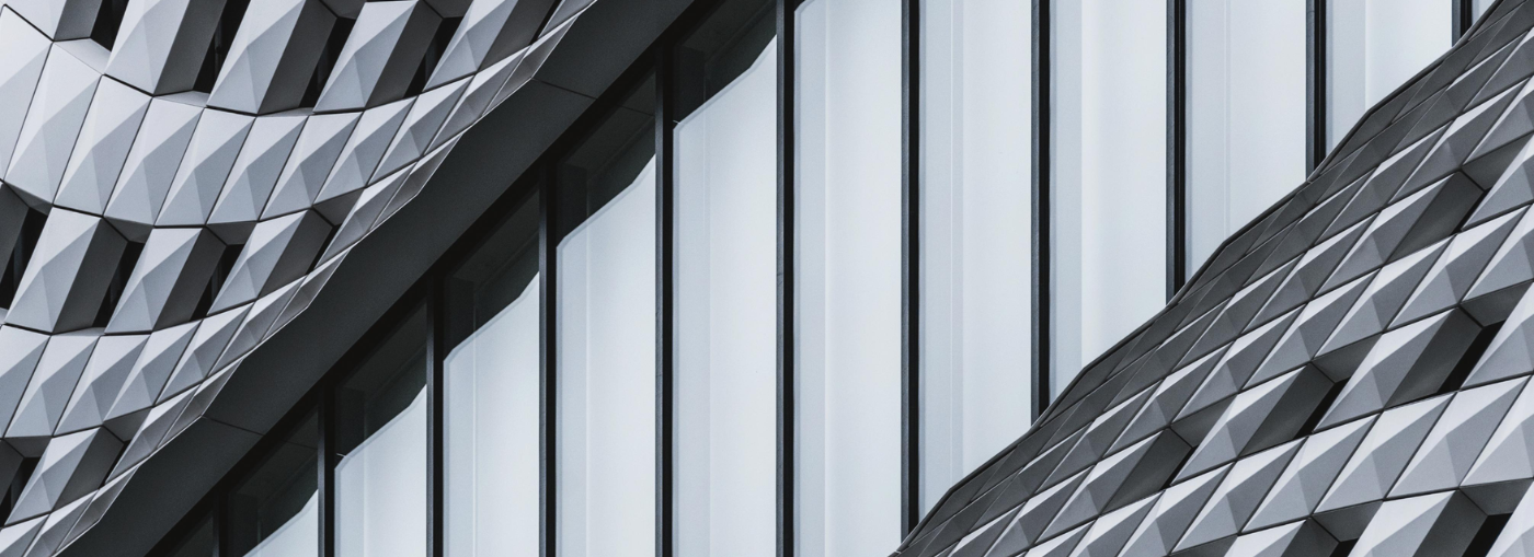 Dettaglio di architettura moderna con facciate geometriche metalliche e ampie vetrate, simbolo di innovazione e design.