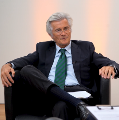 Persona in abito formale seduta su una poltrona durante un'intervista.